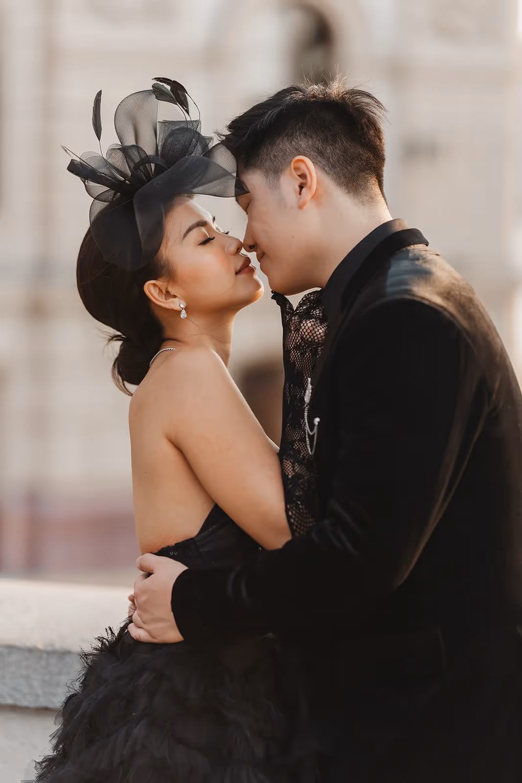 Couple dressed in black embracing closely with eyes closed, about to kiss.