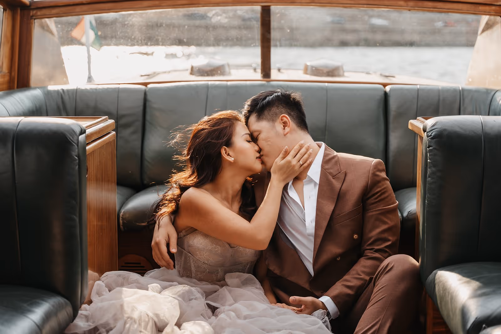 Couple in formal attire sharing a kiss while sitting on the floor of a boat cabin.