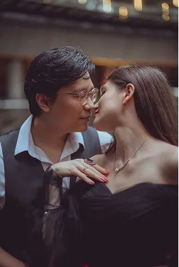 Couple in formal attire sharing an intimate moment, leaning in close with eyes closed.