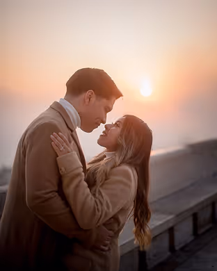Couple embracing closely outdoors at sunset with warm golden light.
